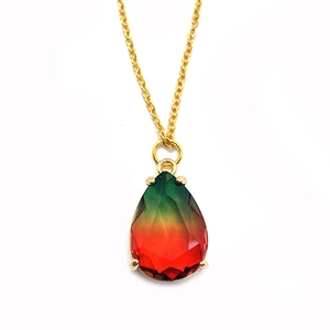 Détail macro du pendentif en cristal facetté avec dégradé de vert et rouge et serti doré