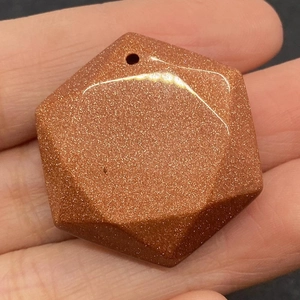 Detailed macro view of a hexagonal goldstone pendant with shimmering copper-colored flecks