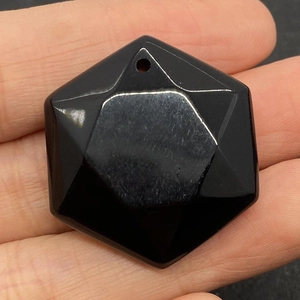 Detailed close-up of a polished hexagonal black agate pendant with engraved hexagram pattern