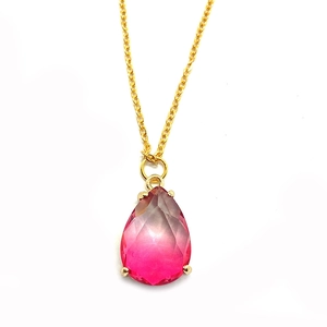 Gros plan sur pendentif cristal rose facetté en forme de goutte avec griffes dorées
