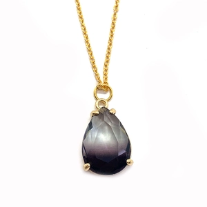 Détail d'un pendentif en cristal facetté avec dégradé de gris foncé à violet intense