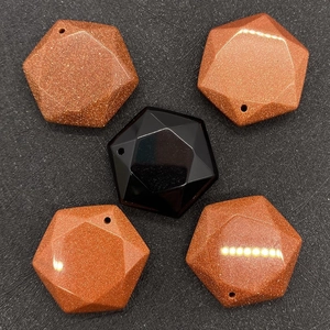 Macro detail of faceted goldstone and black agate hexagonal charms with pre-drilled holes