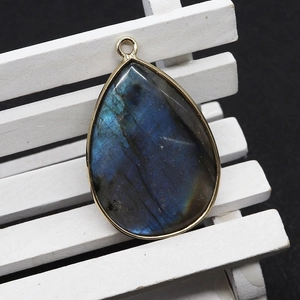 Water drop labradorite stone pendant with gold metal edge on white wooden stand