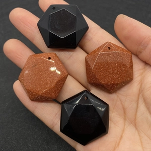 Hexagonal faceted natural stone pendants in black onyx and goldstone held in hand
