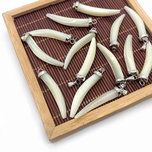 Detailed macro view of white shell horn pendants with silver clasps on a bamboo mat