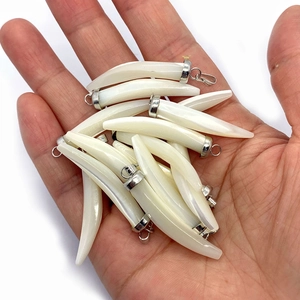 Detailed view of hand-held natural shell pendants in chili shape with silver clasps