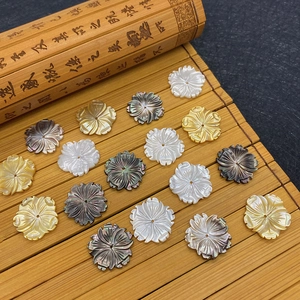 Geschnitzte Muschelperlen in Blumenform in Weiß und Gold auf Bambushintergrund