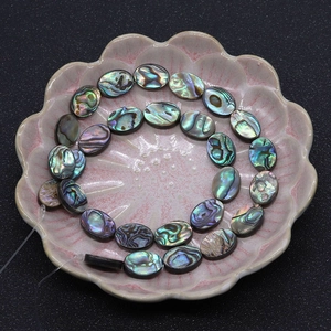 Detailansicht der irisierenden Abalone-Muschelperlen in Keramikschale für Schmuckherstellung