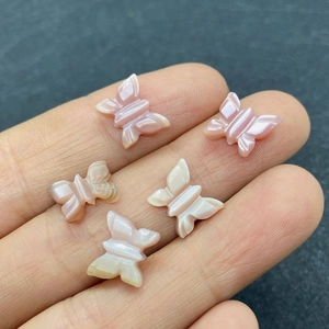 Détail de cinq petits pendentifs papillon en nacre avec un éclat perlé iridescent