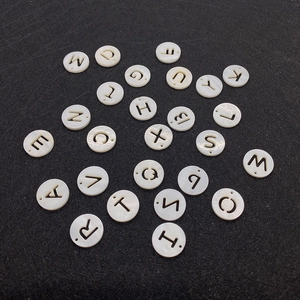 Detailed close-up of 12mm round shell beads with hollowed-out alphabet letters for DIY