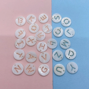 Macro detail of 12mm round shell beads with hollow alphabet letters for DIY jewelry