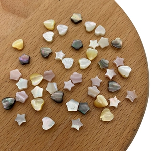 Detail von natürlichen Stern- und Herz-Muschelperlen mit buntem Glanz auf Holztablett