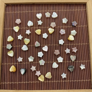 Makroaufnahme von Naturmuschelperlen in Stern- und Herzform auf Bambusmatte für DIY-Schmuck