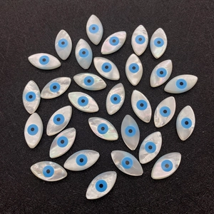 Makro-Detail von Muschelperlen in Markisenform mit Evil Eye Design für DIY-Schmuck