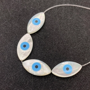 Natürliche Muschel-Perlen im Evil Eye Design mit blau-weißen Akzenten auf schwarzem Netz