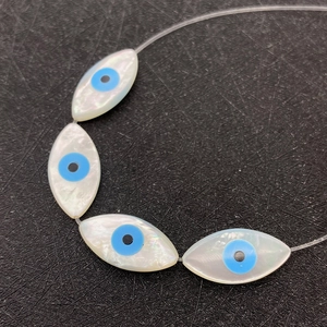Makroaufnahme von marquiseförmigen Muschelperlen mit Evil-Eye-Muster und Perlmuttglanz
