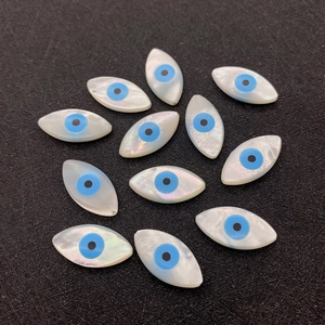 Makro-Detail von zwölf marquise-förmigen Muschel-Perlen mit Evil Eye Effekt für DIY-Schmuck