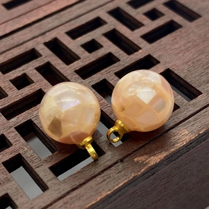 Close-up of spherical natural shell pendants with mosaic texture and golden metal loops