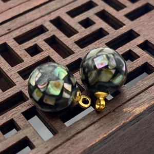 Macro shot of mosaic abalone shell sphere pendants with gold metal ring connectors