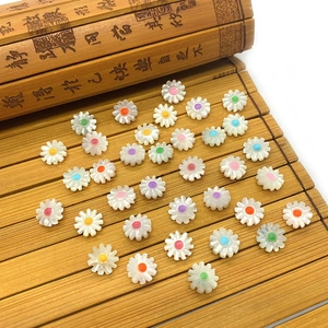 Daisy shell beads with colorful centers displayed on a bamboo scroll for jewelry DIY