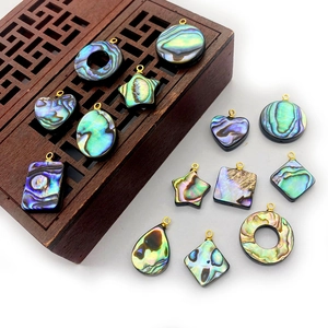 Détail macro de divers pendentifs géométriques en nacre d'abalone avec boucles dorées