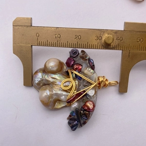 Dettaglio macro del ciondolo fatto a mano con perle barocche e filo dorato metallico