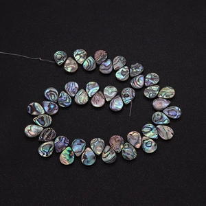 Macro detail of iridescent teardrop abalone shell beads showing natural textures