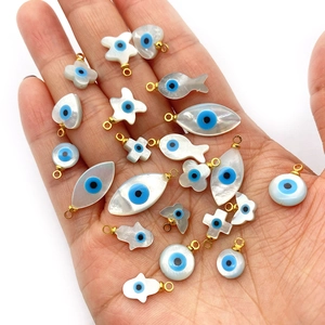 Gros plan de divers pendentifs en nacre avec motifs œil maléfique dans une paume