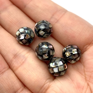 Vue détaillée de perles de mosaïque en nacre noire faites à la main dans une main