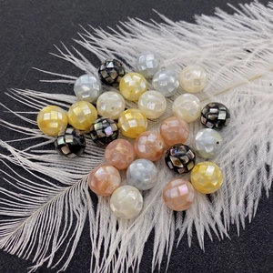 Perles rondes en coquille mosaïque pour bijoux DIY présentées sur une plume blanche