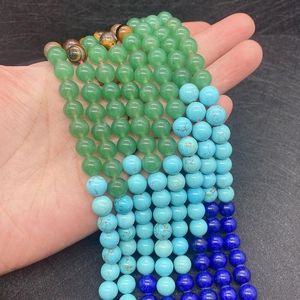 Mix of 6-8mm natural semi-precious stone beads including turquoise and aventurine held in hand
