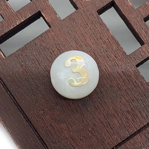 Detail of round shell bead with golden number three for DIY jewelry making