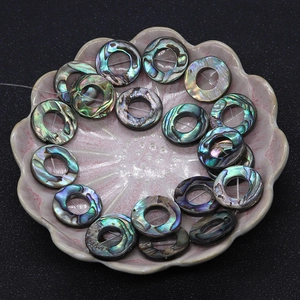 Macro view of natural abalone shell ring beads with iridescent texture in a ceramic dish