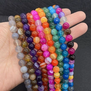 Detailed view of colorful natural striped agate beads held by hand for jewelry DIY