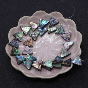 Macro detail of iridescent triangle abalone shell beads on a decorative petal dish