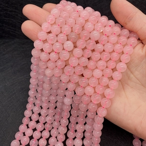 Macro detail of natural translucent pink quartz round beads held by hand showing clarity