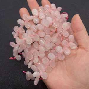 Macro view of teardrop rose quartz beads held in hand for DIY jewelry making crafts