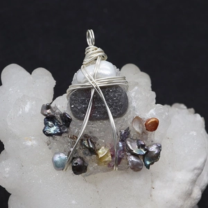 Detailed macro view of handmade wire-wrapped baroque pearl and stone jewelry pendant