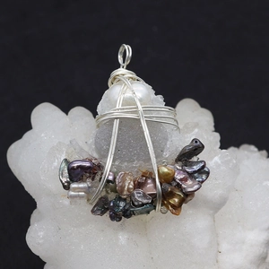 Macro detail of handmade wire wrapped grey stone pendant with irregular pearls on crystal