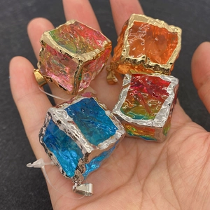 Close-up of four colorful cubic crystal stone pendants with gold and silver metal edges
