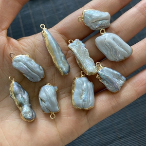 Baroque freshwater pearl pendants with gold plated edges shown held in hand