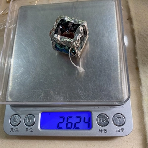Macro view showing natural stone cube pendant weight at 26.24g on a digital scale
