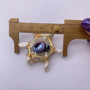 Measurement of irregular baroque pearl pendant with blue stone and gold wire using a caliper