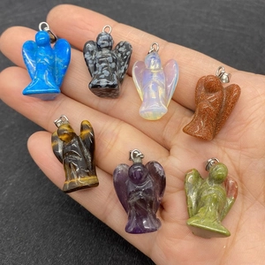 Detailed view of seven colorful natural stone angel pendants held in hand for size context