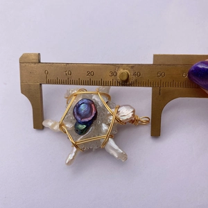 Macro shot of handmade wire-wrapped pearl pendant measured with a brass caliper