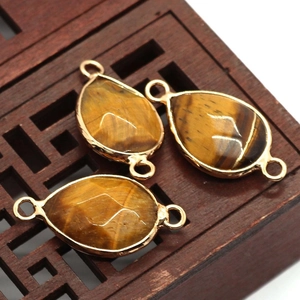 Macro shot of three teardrop-shaped tiger eye stone pendants with golden metal edges