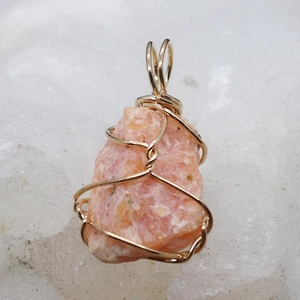 Macro view of handmade wire-wrapped pink crystal stone pendant with gold wire details