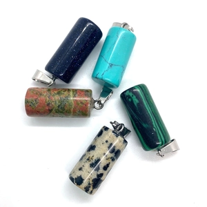 Set of five cylindrical natural stone pendants with silver metal bails on white background