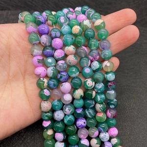 Close-up of colorful dragon vein agate beads for jewelry making held by a hand