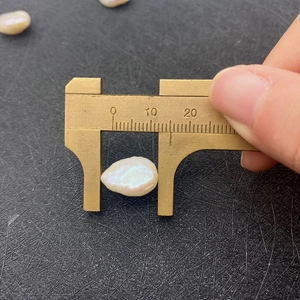 Makroaufnahme einer 12 mm Barockperle bei der Messung mit einem Messschieber im Detail